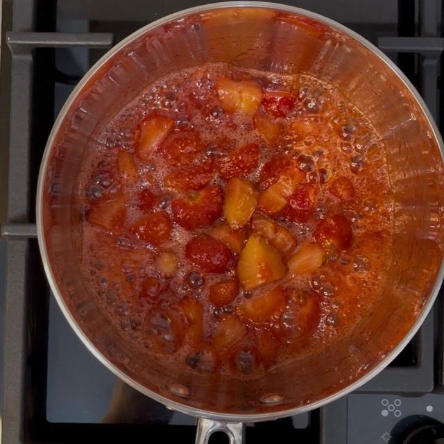 Cucchiaio di legno che mescola la composta di fragole.