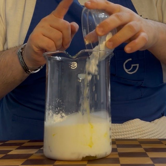 Uova, panna e amido di mais in un contenitore alto.