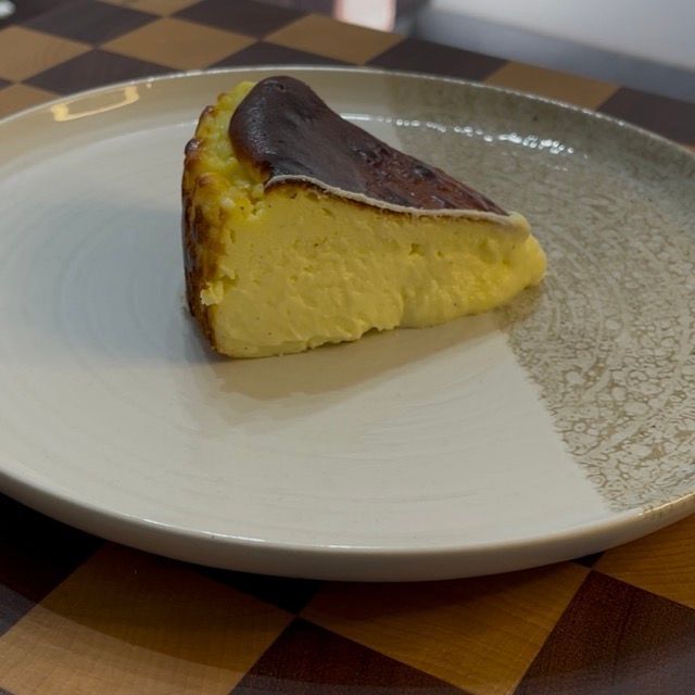 Fetta di cheesecake basca su un piattino che mostra il cuore cremoso.