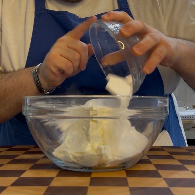 Ingredienti in una ciotola: formaggio spalmabile, zucchero a velo e semi di vaniglia