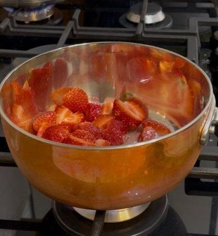 Composta di fragole che sobbolle in un pentolino sul fuoco.