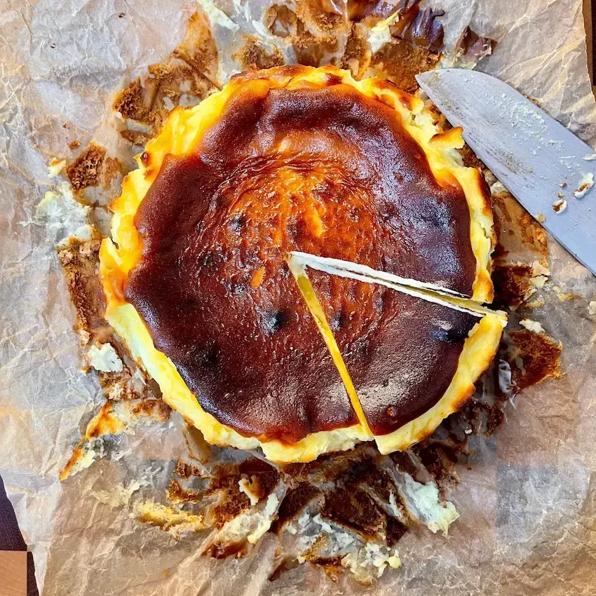 Cheesecake Basca intera con la sua tipica superficie scura e caramellizata, effetto 'bruciato