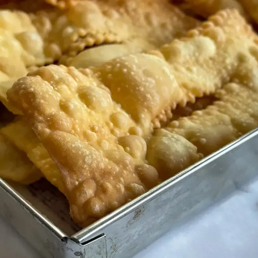 Vassoio di chiacchiere di carnevale bollose e friabili spolverate con zucchero a velo.