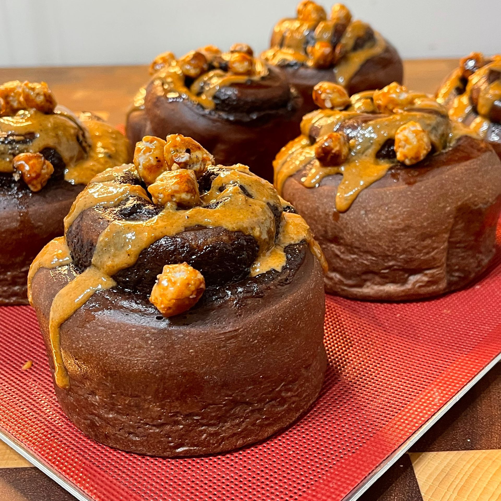 Un gruppo di rotoli di cioccolato e cannella con burro di arachidi e salsa al caramello su un tavolo.