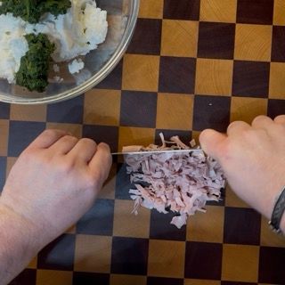 Tritatura della mortadella da aggiungere ai conchiglioni ripieni ricotta e spinaci.