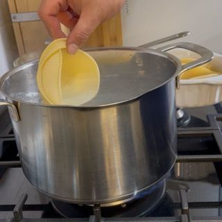 Conchiglioni giganti che cuociono in acqua bollente salata per metà tempo.