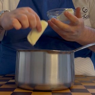 Aggiunta del burro freddo nella salsa di pomodoro liscia per i conchiglioni ripieni sfiziosi.