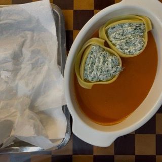 Posizionamento ordinato dei conchiglioni ripieni nella pirofila sopra la salsa.