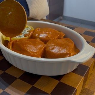 Teglia di conchiglioni ripieni al forno pronta per la cottura finale.