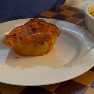 Piatto finito di conchiglioni ripieni al forno fumanti e cremosi.