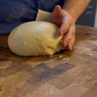 Mani che formano una pagnotta liscia con l'impasto del Cramique.