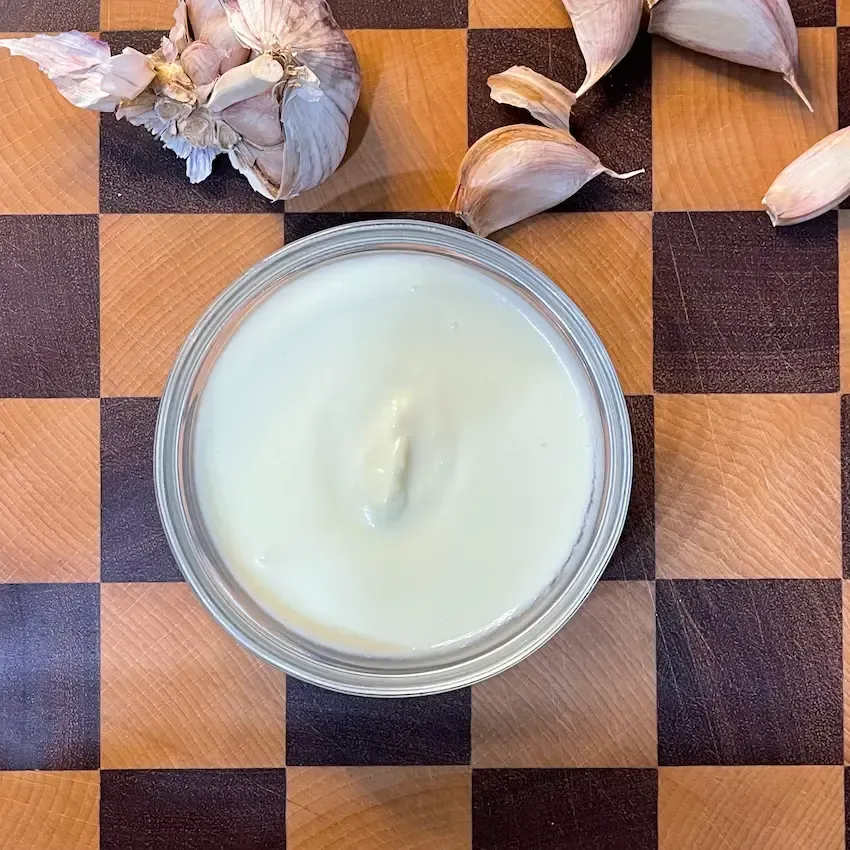 Una ciotolina di ceramica piena di crema di aglio fatta in casa, bianca, vellutata e soffice