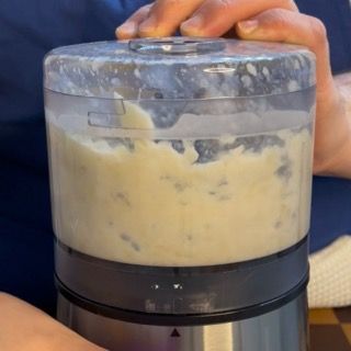 Unione controllata di un ultimo cucchiaio di latte per perfezionare la consistenza della crema di aglio ricetta veloce.