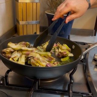 Una persona sta mescolando le verdure in una padella sul fornello