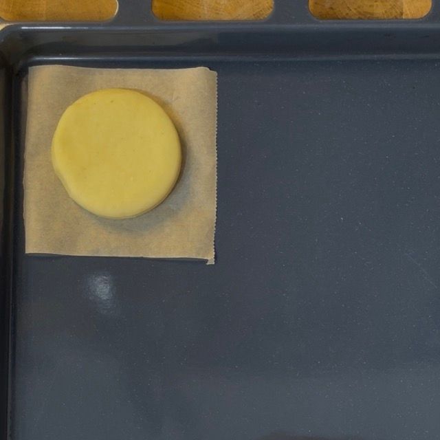 Dischi di pasta per krapfen adagiati su quadrati di carta da forno.