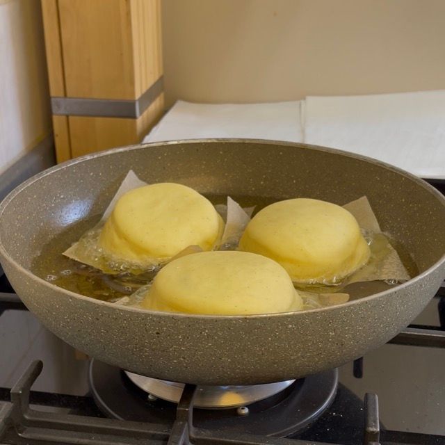 Krapfen che friggono e si gonfiano nell'olio.