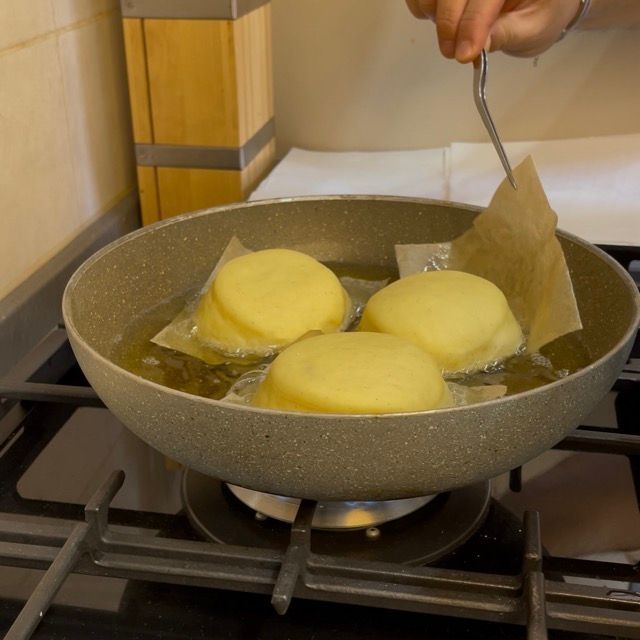 Pinza che rimuove la carta da forno dall'olio bollente.