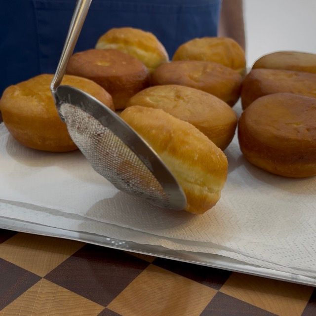 Krapfen e bomboloni che scolano su un vassoio con carta assorbente