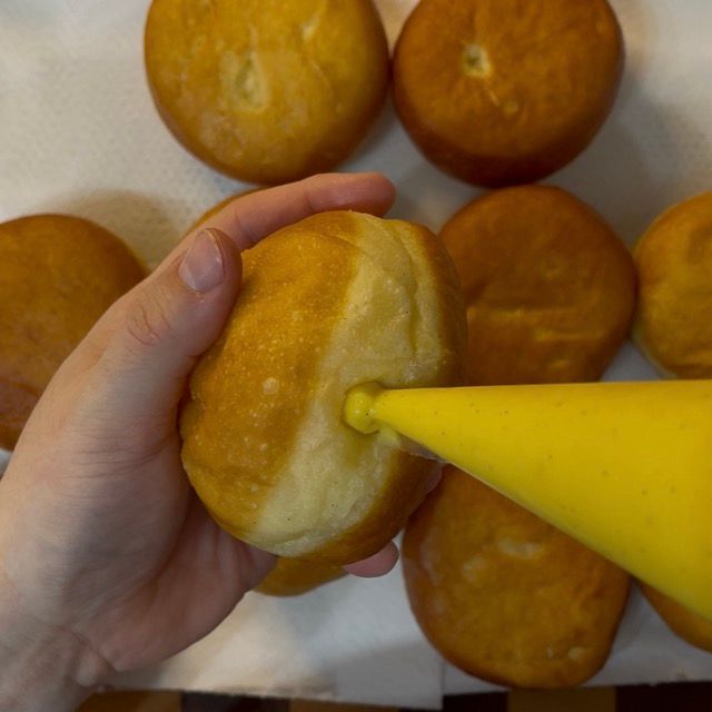 Sac a poche che farcisce abbondantemente un krapfen con la crema.