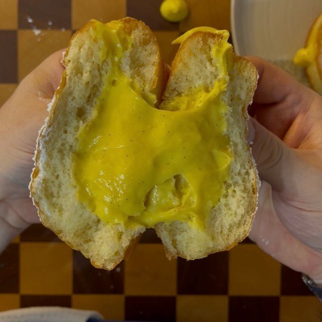 Primo piano di un krapfen ripieno di crema, pronto per essere mangiato.