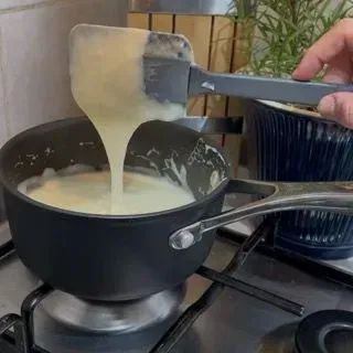 Frusta che mescola energicamente la besciamella per evitare grumi