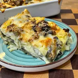 Porzione di lasagne alle melanzane al piatto, che mostra i ricchi strati di pasta, melanzane grigliate e hummus di ceci cremoso.