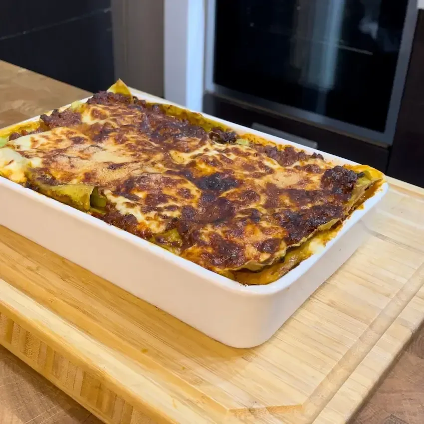 Lasagne alla bolognese appena sfornate in una teglia, con una crosta dorata e croccante di Parmigiano Reggiano.