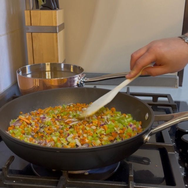 Soffritto dorato pronto per l'aggiunta del pesce nel tegame.