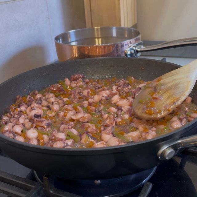 Polpo insaporito con sale e pepe durante la fase di rosolatura iniziale.