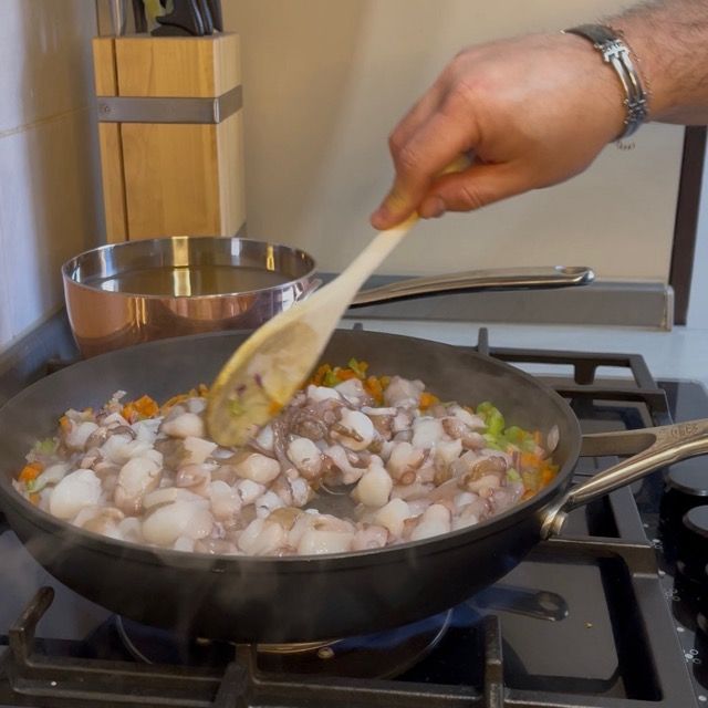 Rosolatura del polpo in padella per sigillare i succhi e il sapore.