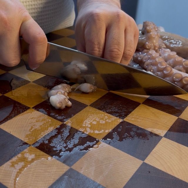 Taglio dei tentacoli del polpo a pezzetti per un ragù corposo.