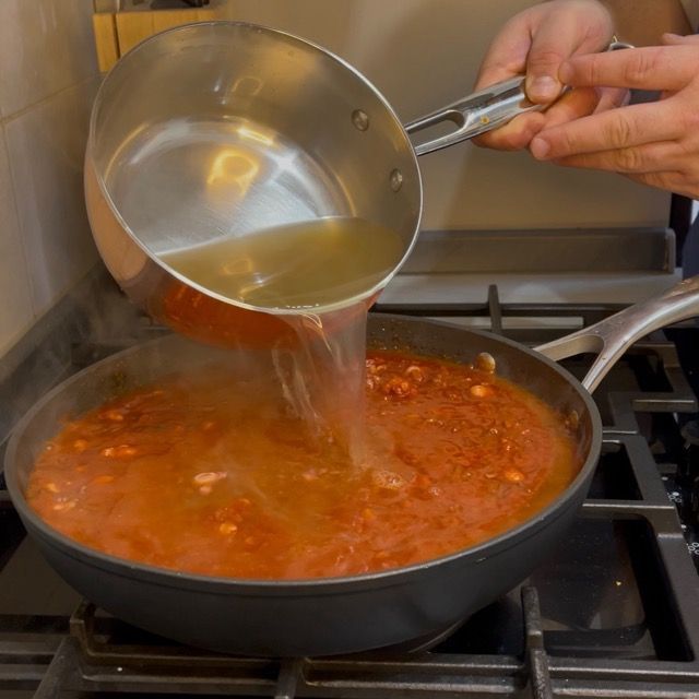 Ragù di polpo che sobbolle a fuoco medio coperto dal brodo.