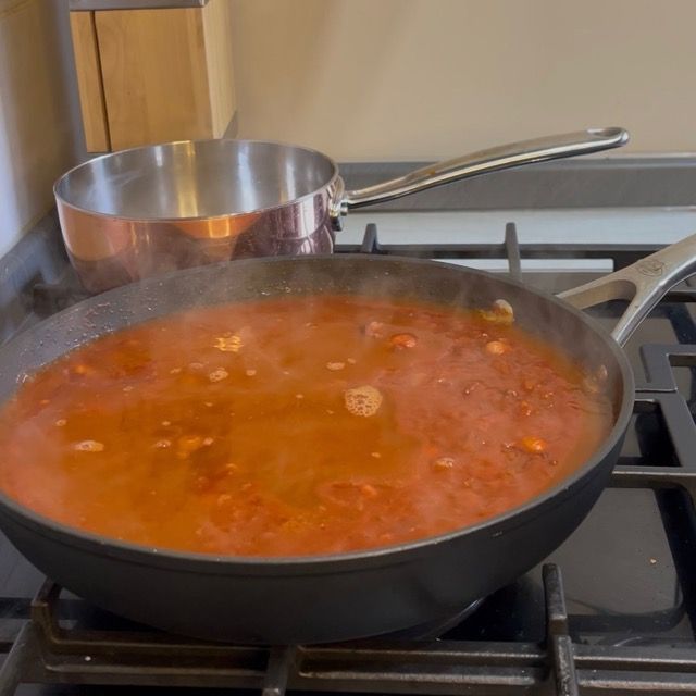 Aggiunta del brodo di pesce al ragù di polpo in cottura.