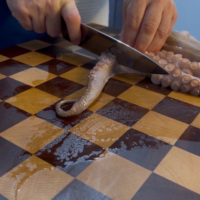 Pulizia del polpo fresco sul tagliere prima della cottura.