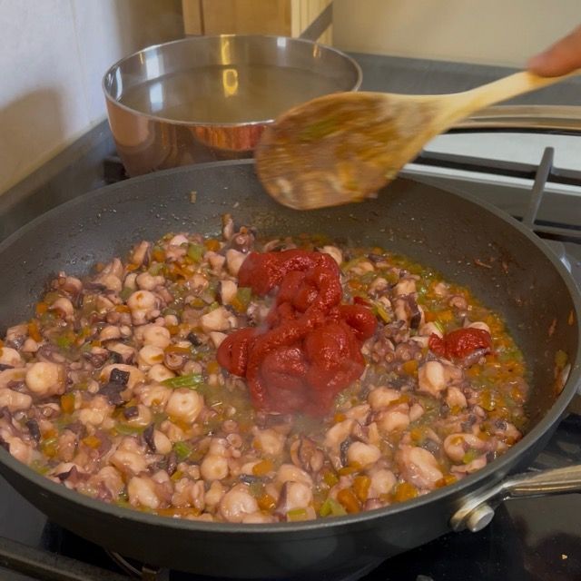 Aggiunta del concentrato di pomodoro al polpo rosolato.