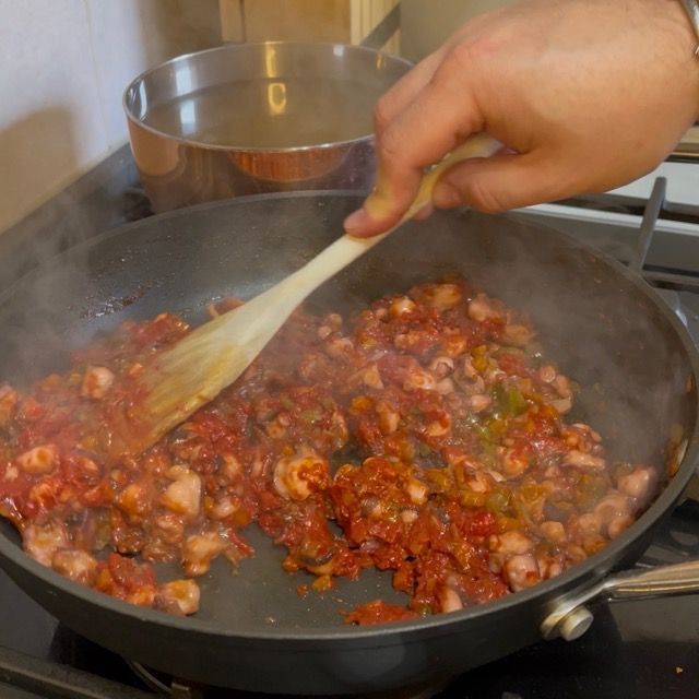 Tostatura del concentrato di pomodoro per un ragù di polpo scuro e denso.
