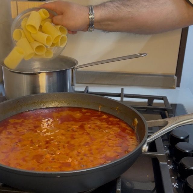 Paccheri che cuociono in acqua bollente salata prima di essere scolati.