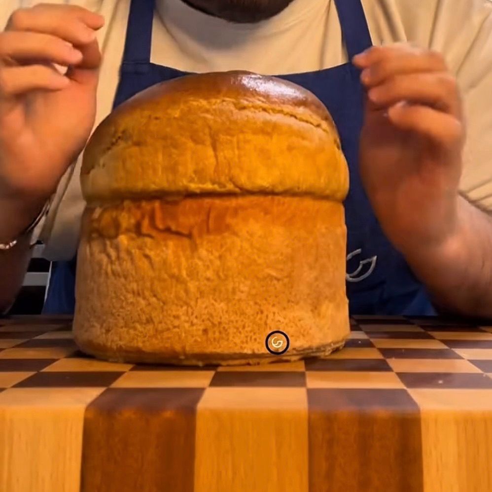 Panettone gastronomico appena sfornato e dorato, ancora nello stampo.