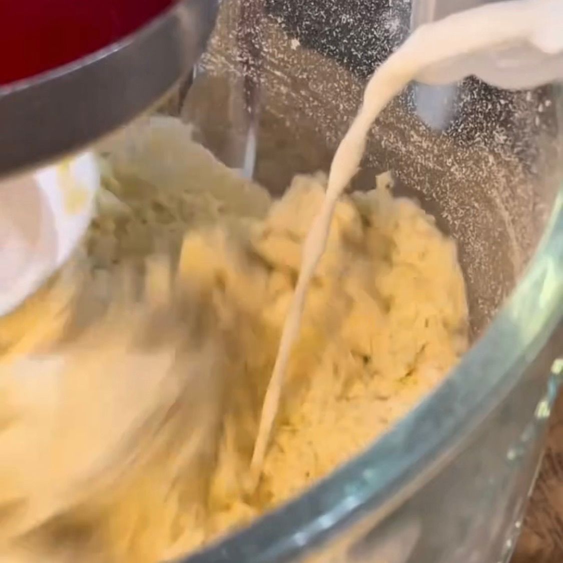 Latte a temperatura ambiente versato a filo sull'impasto in lavorazione