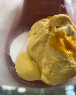 Un primo piano di una sostanza gialla in una tazza graduata