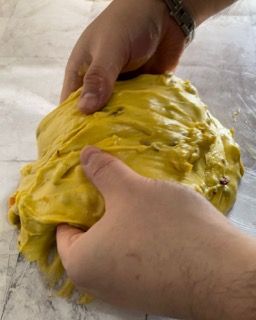 Una persona tiene in mano un pezzo di pasta gialla.