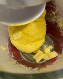Un primo piano di un mixer con impasto giallo e burro