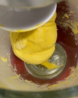 Una palla gialla di pasta viene mescolata in un'impastatrice