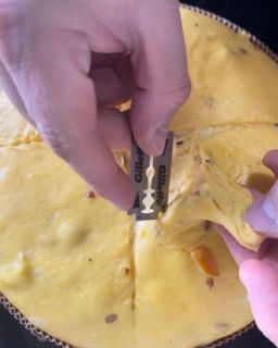 Una persona tiene in mano un rasoio Gillette sopra una pizza