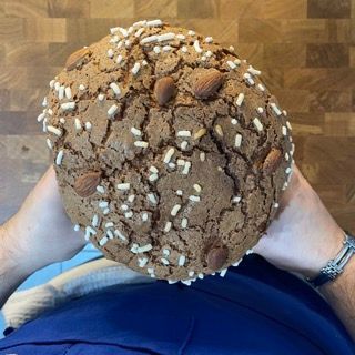 Una persona tiene in mano un biscotto con mandorle e granella sopra