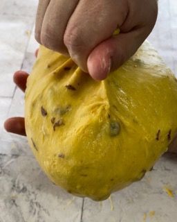 Una persona tiene in mano una palla di pasta gialla.