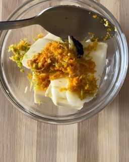 Una ciotola di cibo con un cucchiaio dentro su un tavolo di legno.