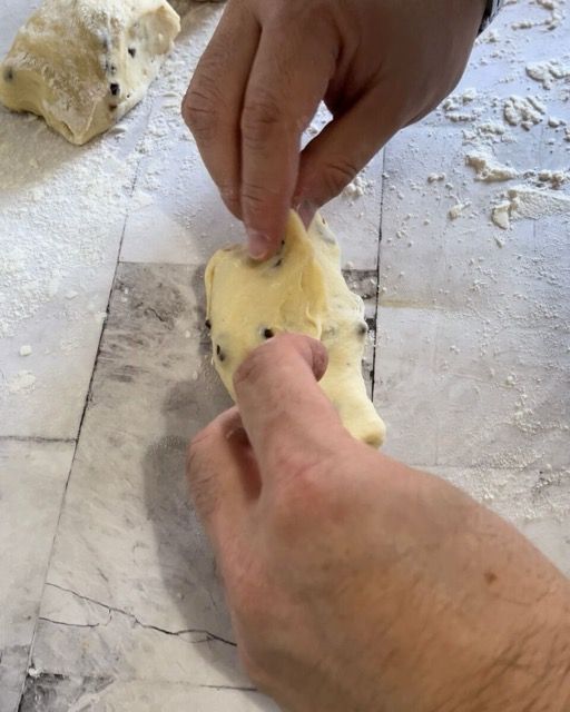 Mani che formano un panino arrotolando una porzione di impasto.