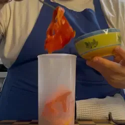 Falde di peperoni spellati in un boccale alto con olio, sale e pepe