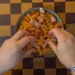 Aggiunta di tonno a pezzetti e del pane aromatizzato croccante sopra la pasta.